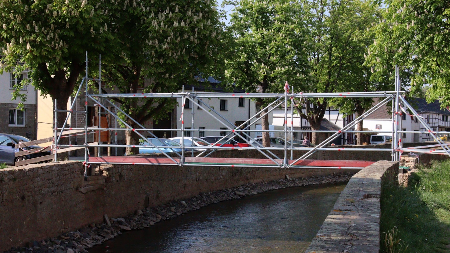 Das Foto zeigte eine provisorische Brücke an der Ley in Iversheim, über die die Erft in Richtung Kindergarten überquert werden kann. Dort früheren Erftbrücken in Iversheim wurden durch die Flut zerstört. Sie sollen in Kürze saniert werden.