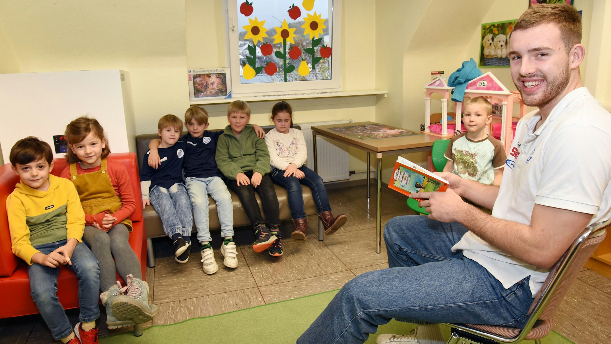 VfL-Handballer Bruno Eickoff liest vor sieben Erstklässlern aus einem Janosch-Buch.