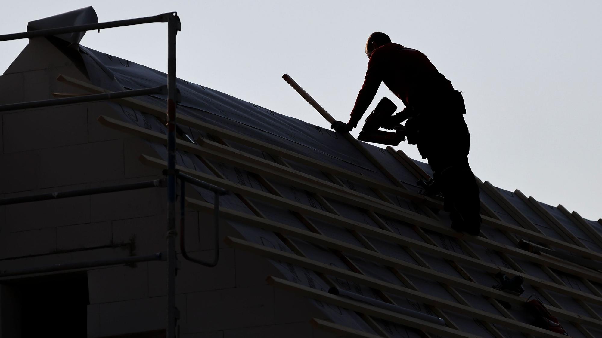 Ein Dachdecker arbeitet auf einem Einfamilienhaus. Angesichts steigender Zinsen und Baukosten rückt der Traum vom Eigenheim für immer mehr Menschen in die Ferne.