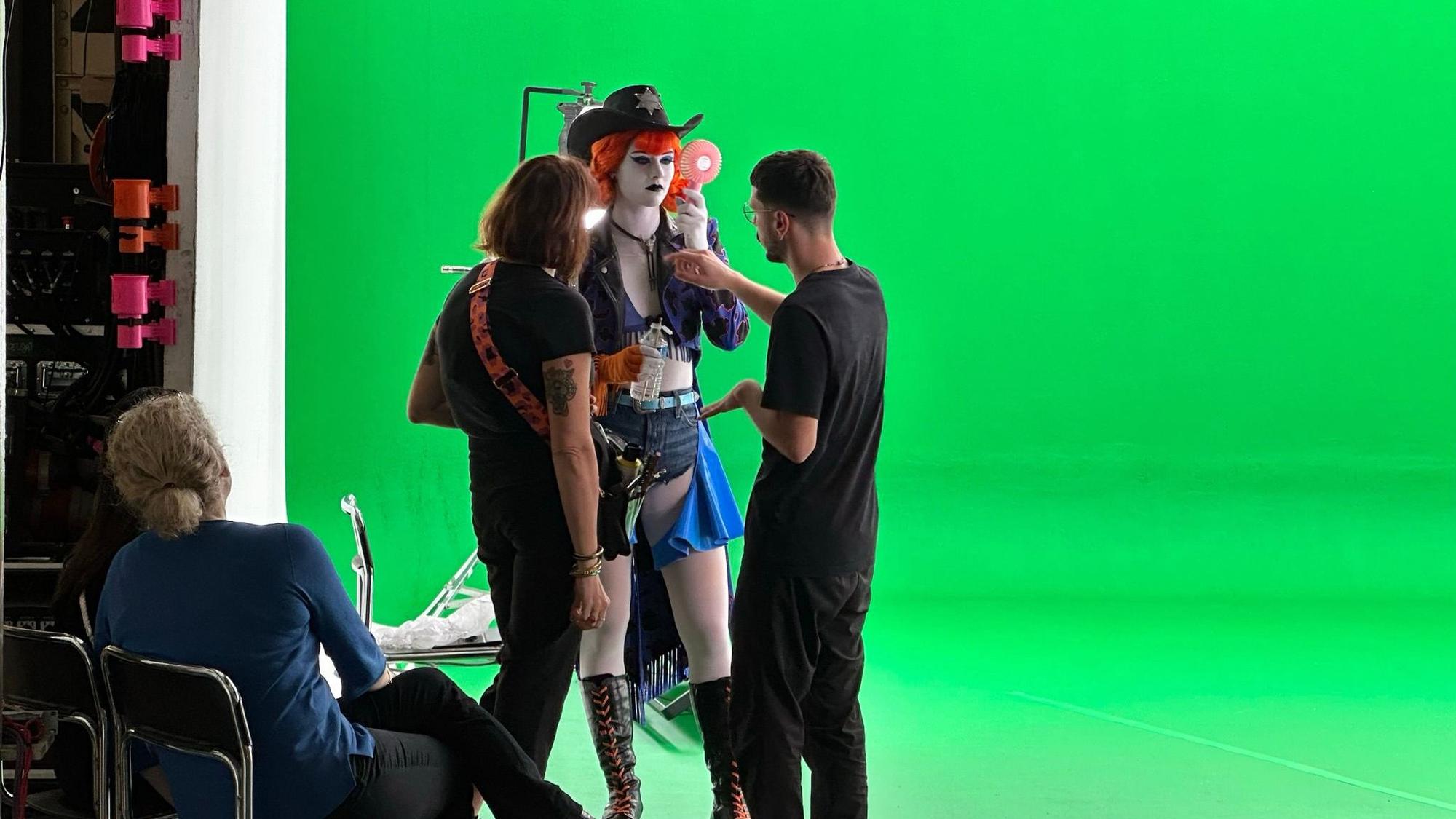 Eine Tänzerin steht vor einem Greenscreen und bekommt Anweisungen.