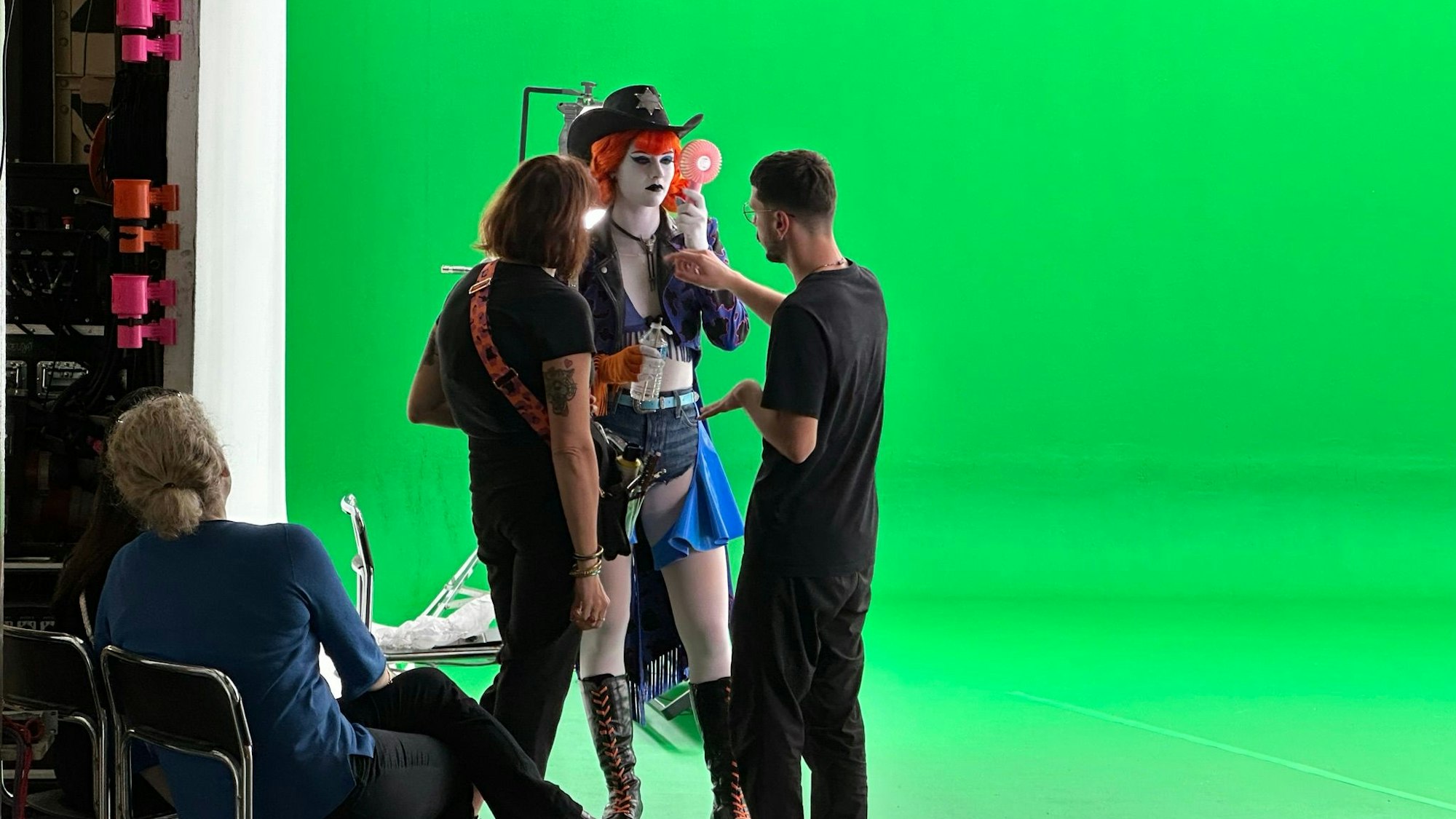 Eine Tänzerin steht vor einem Greenscreen und bekommt Anweisungen.