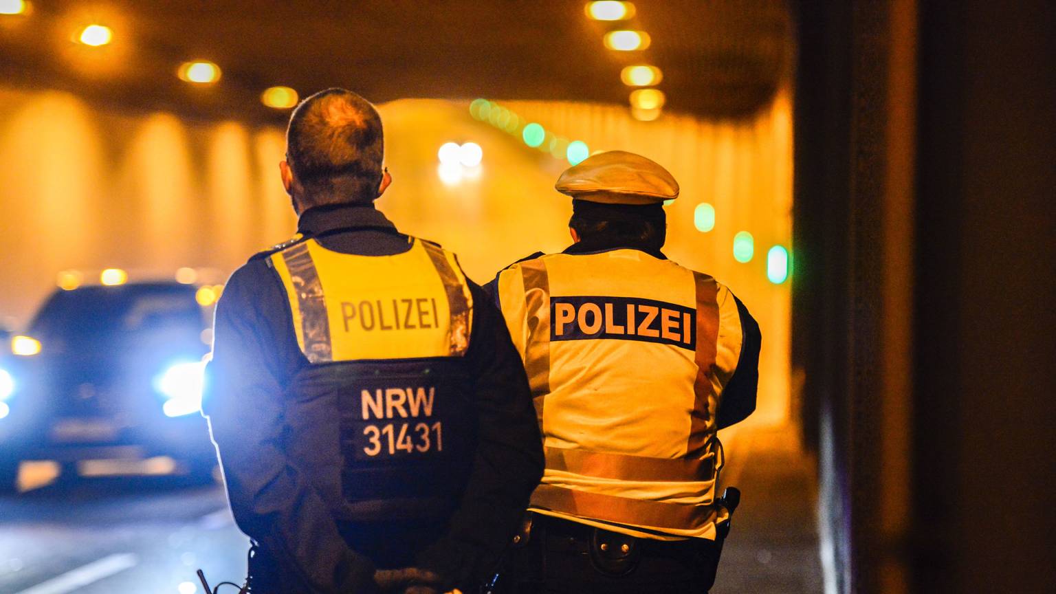 Zwei Polizisten stehen mit einer Kelle in einem Tunnel. Ein Auto kommt ihnen entgegen.