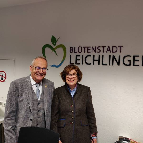 Schiedsfrau Gisela Becher steht mit ihrem Vorgänger Gert Schulze im Rathausfoyer vor dem Schriftzug Blütenstadt Leichlingen