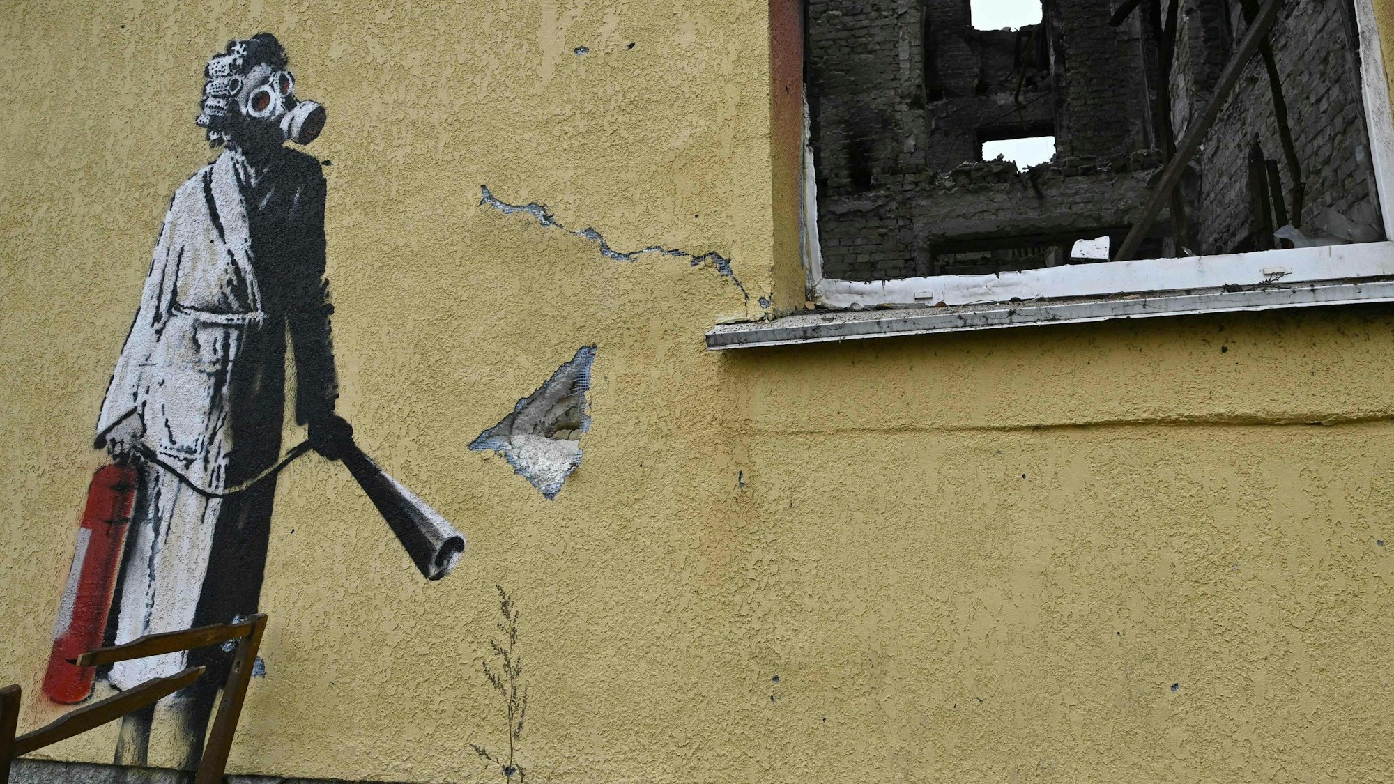 Auf einer zerschossenen Häuserwand in der Ukraine ist ein Werk von Banksy zu sehen.