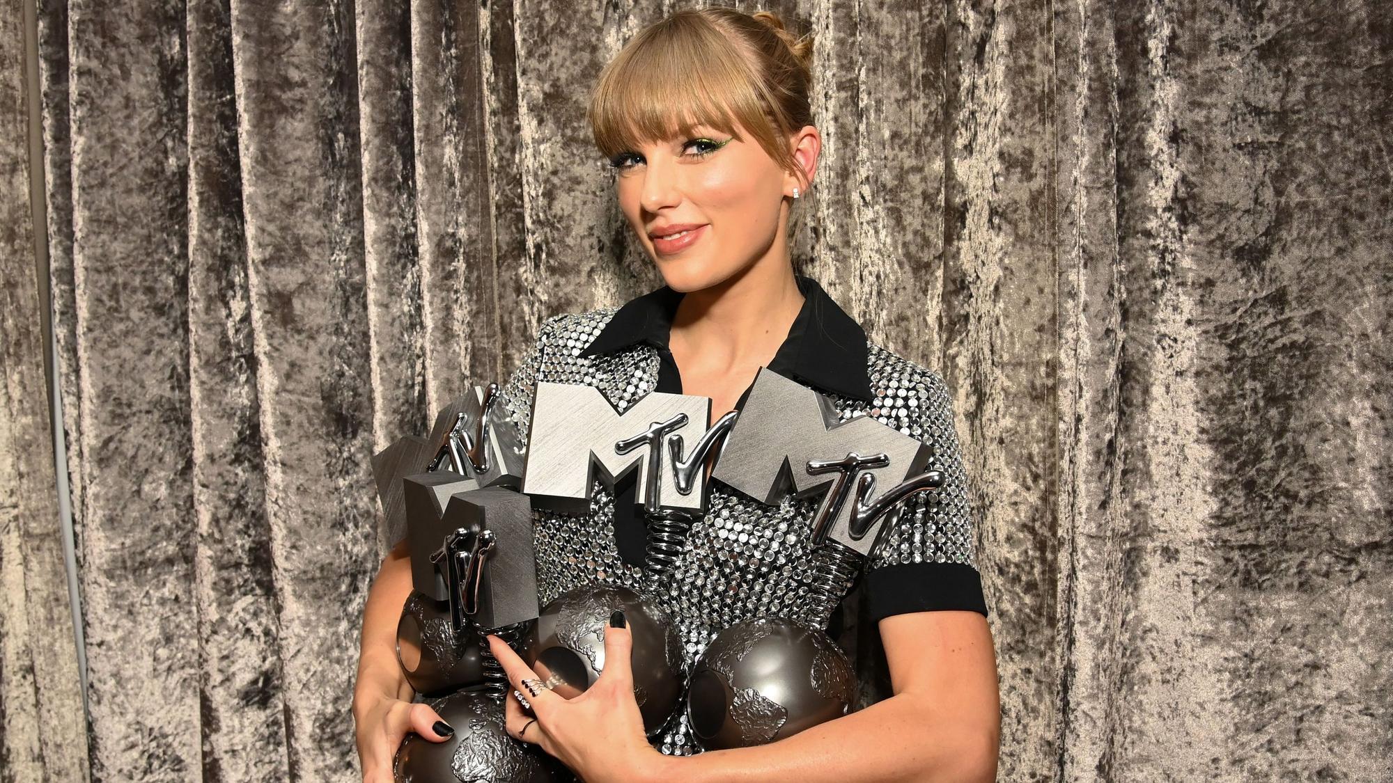 Taylor Swift hält am 13. November 2022 einen Arm voll MTV Europe Music Awards. Sie trägt einen Dutt und ein Glitzerkleid in Schwarz.