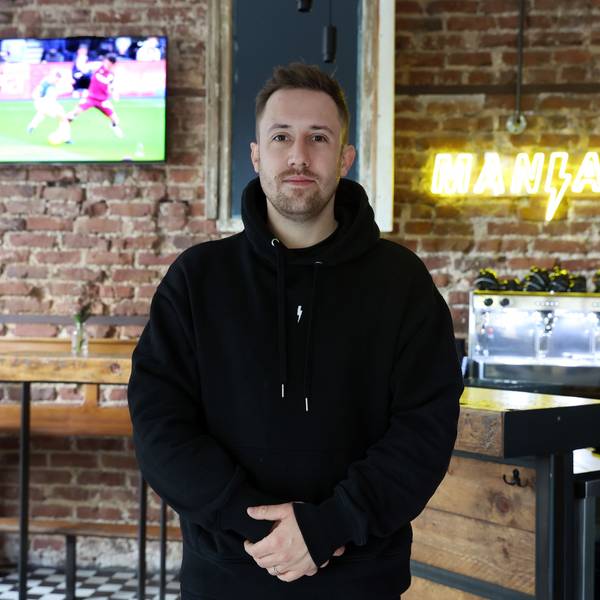 Nicolas Gottschalk, der Wirt der Fußballkneipe Brüsseler dem Brüsseler Platz, steht im Gastraum vor der Theke mit verschränkten Händen. An der Wand hängt ein Bildschirm, auf dem ein Fußballspiel gezeigt wird.