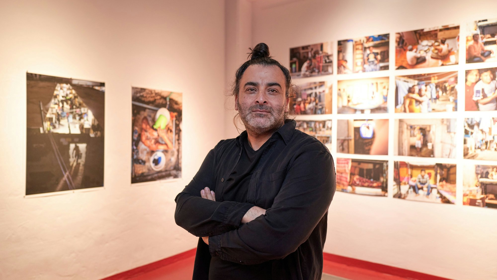 Der Künstler Mohamed Badarne vor Fotos der Ausstellung im Deutschen Sport- und Olympiamuseum