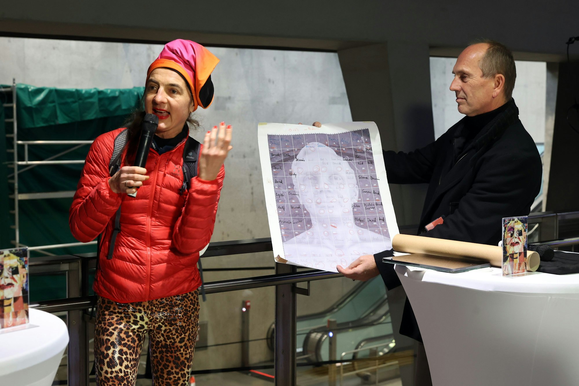 Einweihung des Kunstwerks in der Kölner U-Bahn Haltestelle Breslauer Platz. die Kölner Künstlerin Marion Anna Simon hält eine Ansprache. Ein schwarz gekleideter Mann neben ihr hält einen kleineren Ausdruck des Kunstwerks.