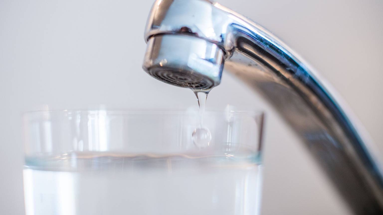 Wasser aus einem Wasserhahn läuft in ein Glas.