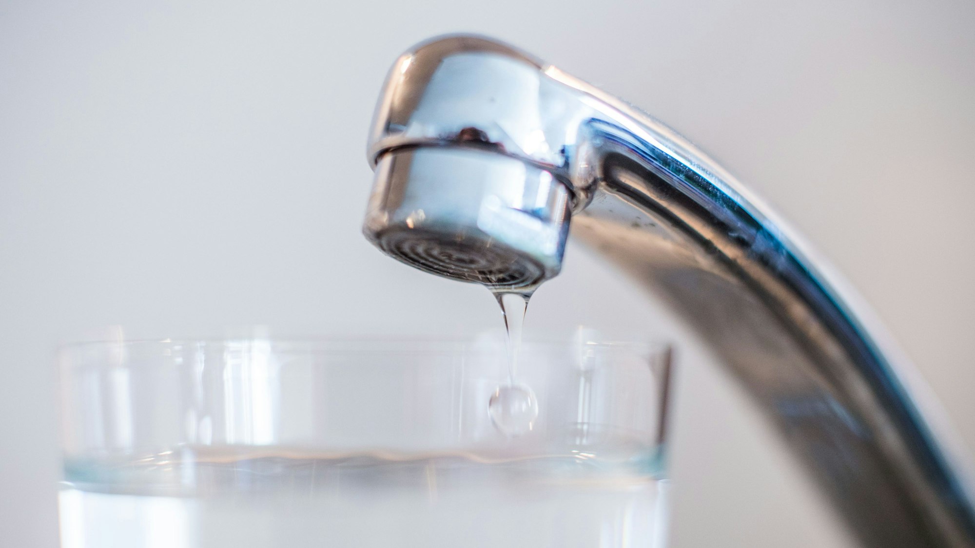 Wasser aus einem Wasserhahn läuft in ein Glas.