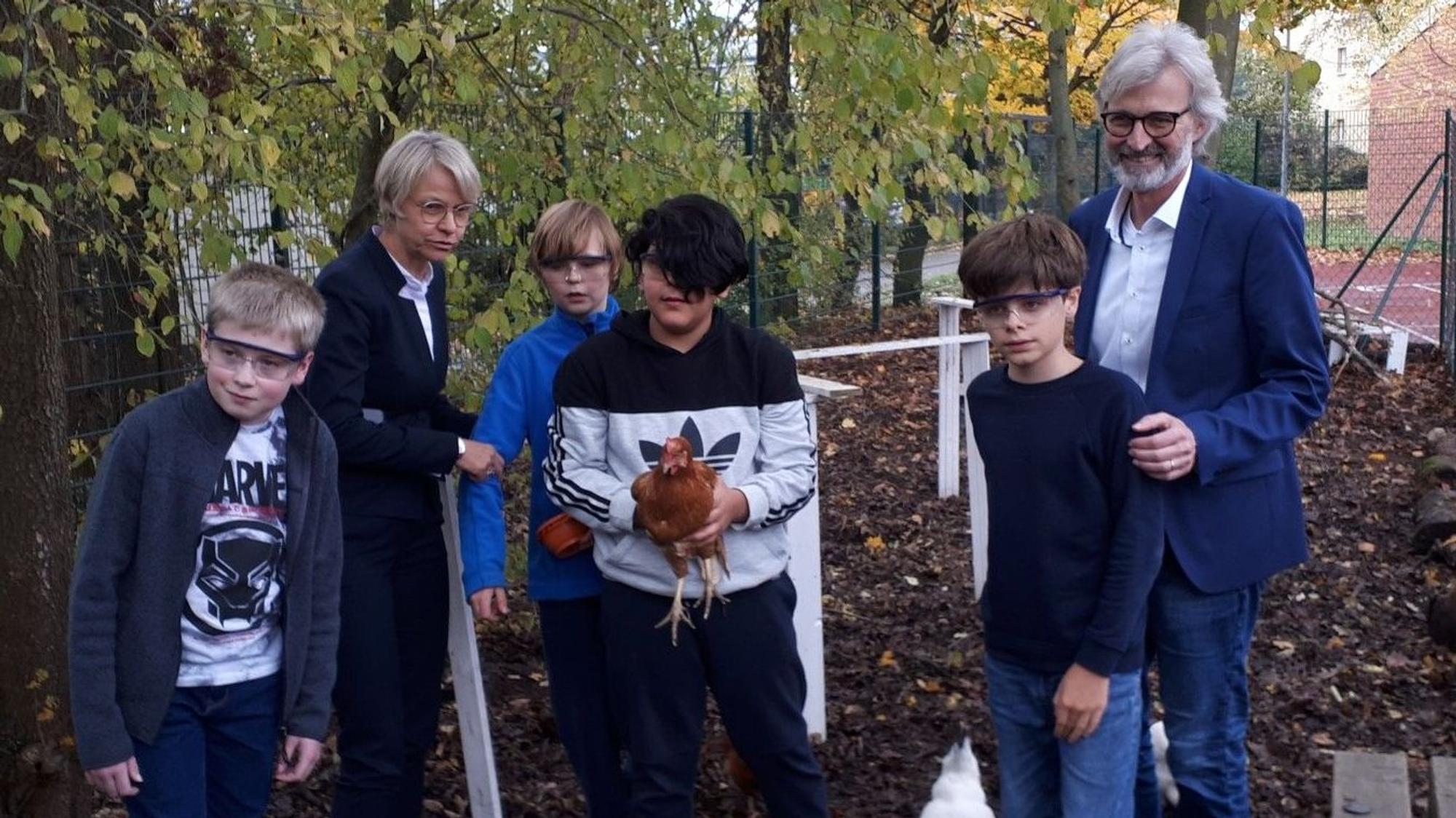 Dorothee Feller (2.v.l.) und Michael Boes-Schulte (r.) mit Schülern im Hühnerstall an der Kölner Förderschule.