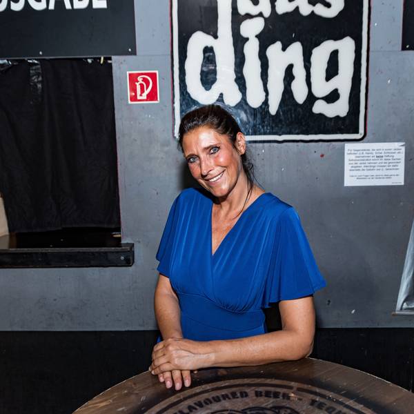 Claudia Wecker, im blauen Kleid, fotografiert im „Studentenclub Das Ding“, den sie betreibt.