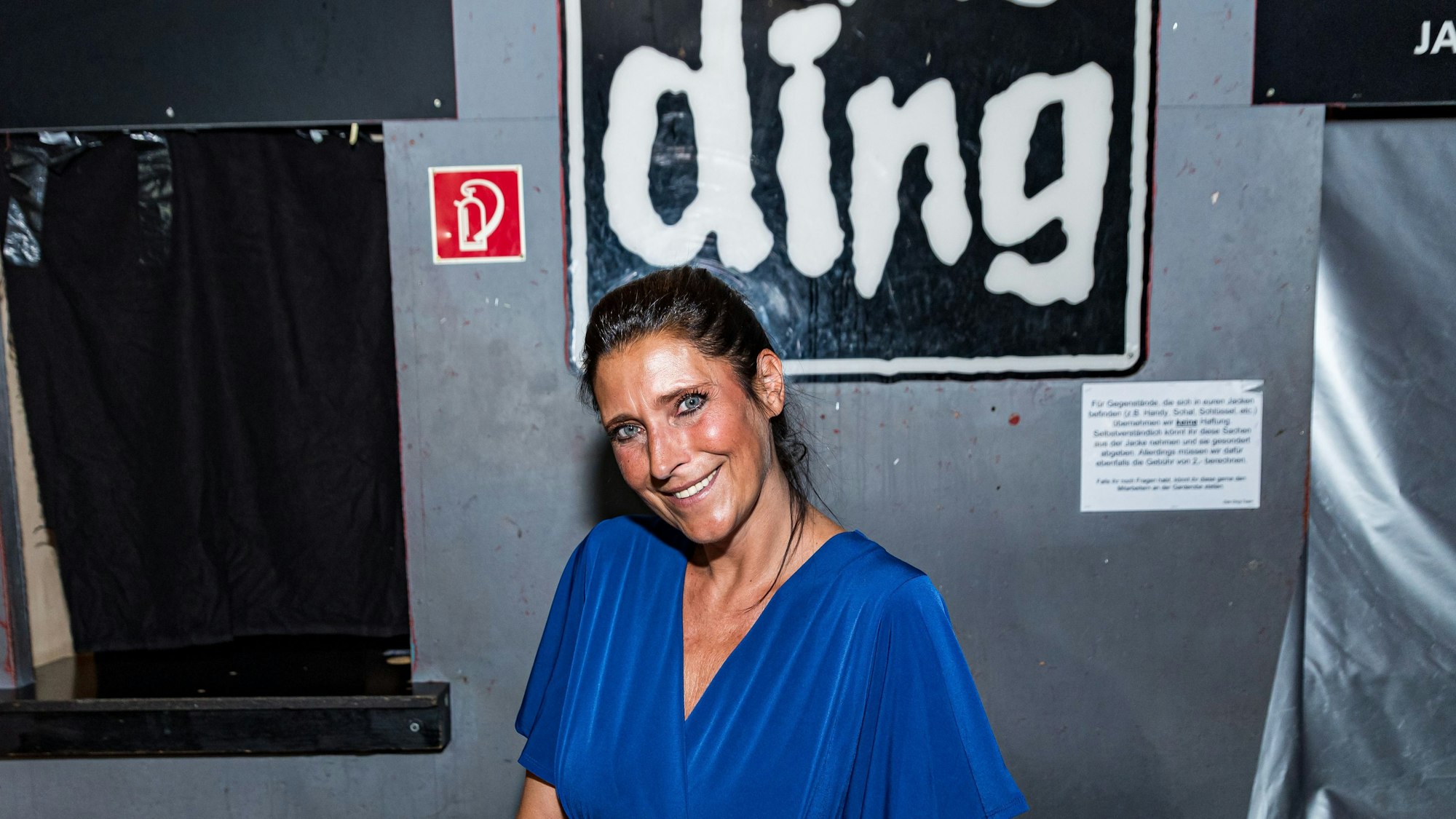 Claudia Wecker, im blauen Kleid, fotografiert im „Studentenclub Das Ding“, den sie betreibt.