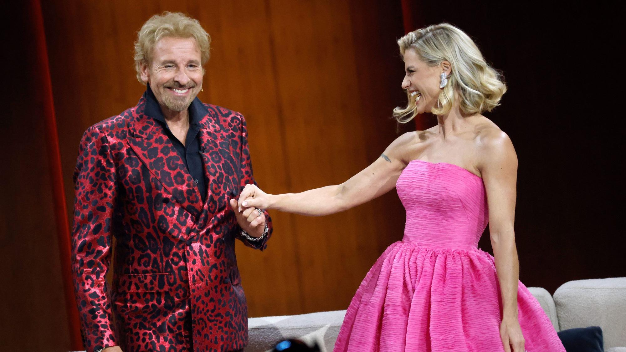 Thomas Gottschalk im roten Leoprint-Anzug und Michelle Hunziker in einem pinken Kleid stehen in der Messehalle in Friedrichshafen während der "Wetten, dass..?"-Sendung