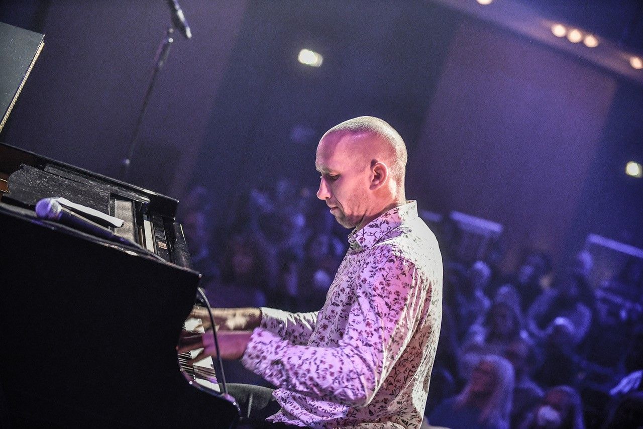 Jazz-Pianist Ryan Hanseler trägt ein Hemd mit Blumenmuster und sitzt an einem Klavier.
