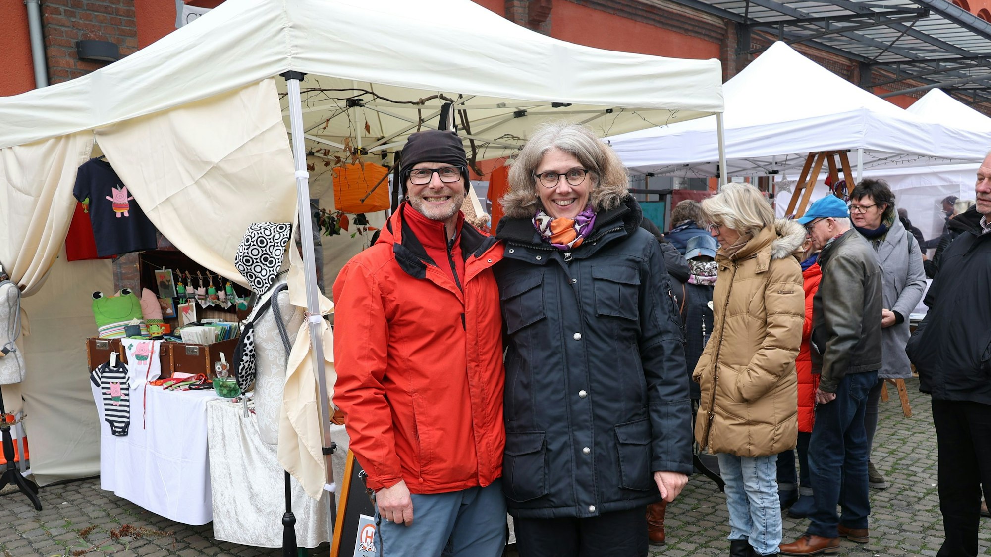 Ein Mann und eine Frau stehen vor einem Pavillon auf dem Weihnachtsbasar.