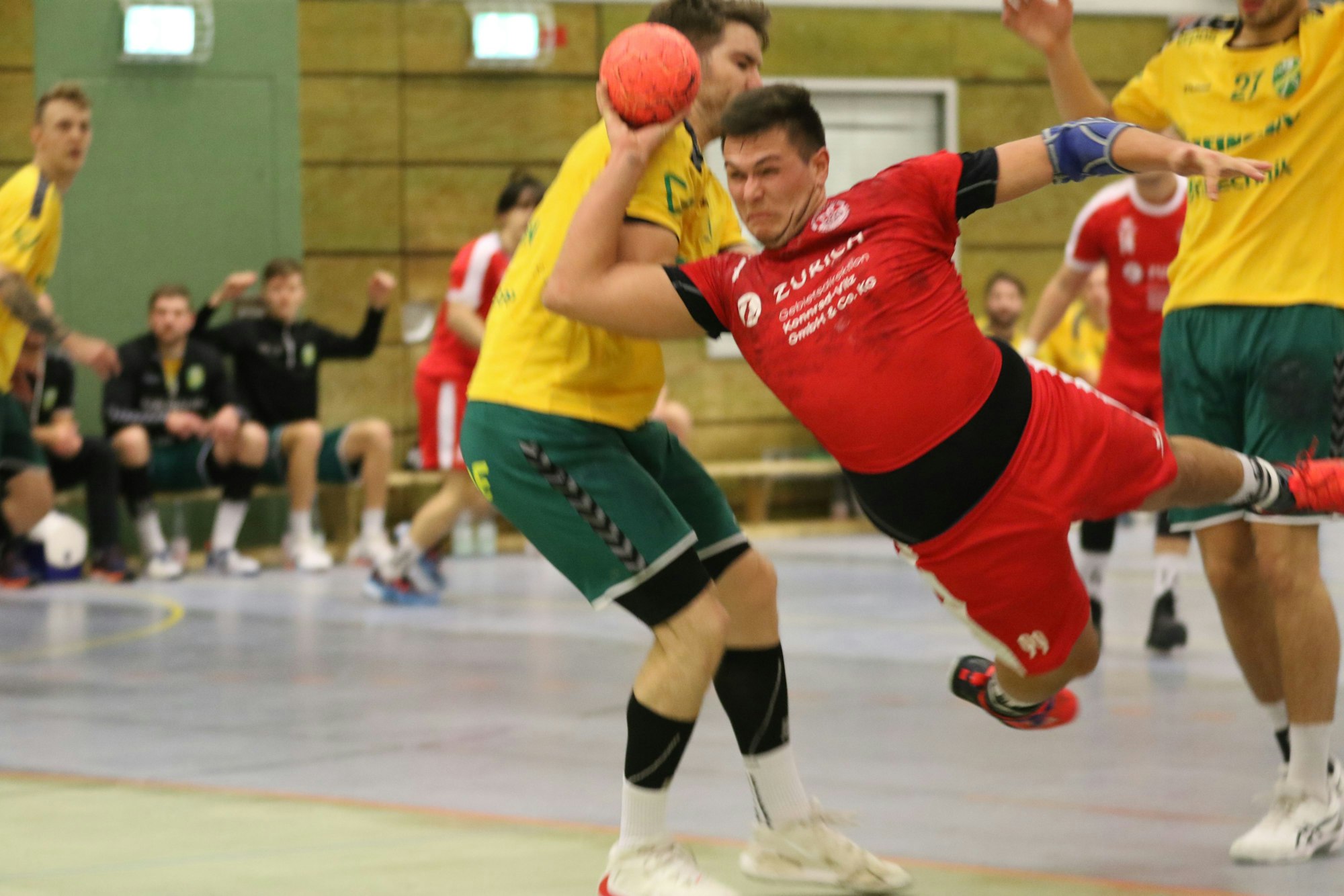 TV-Palmersheim-Spieler Lukas Königshoven liegt beinahe waagerecht in der Luft und wirf, gestört von Verteidigern des HC Gelpe/Strombach, aufs Tor.