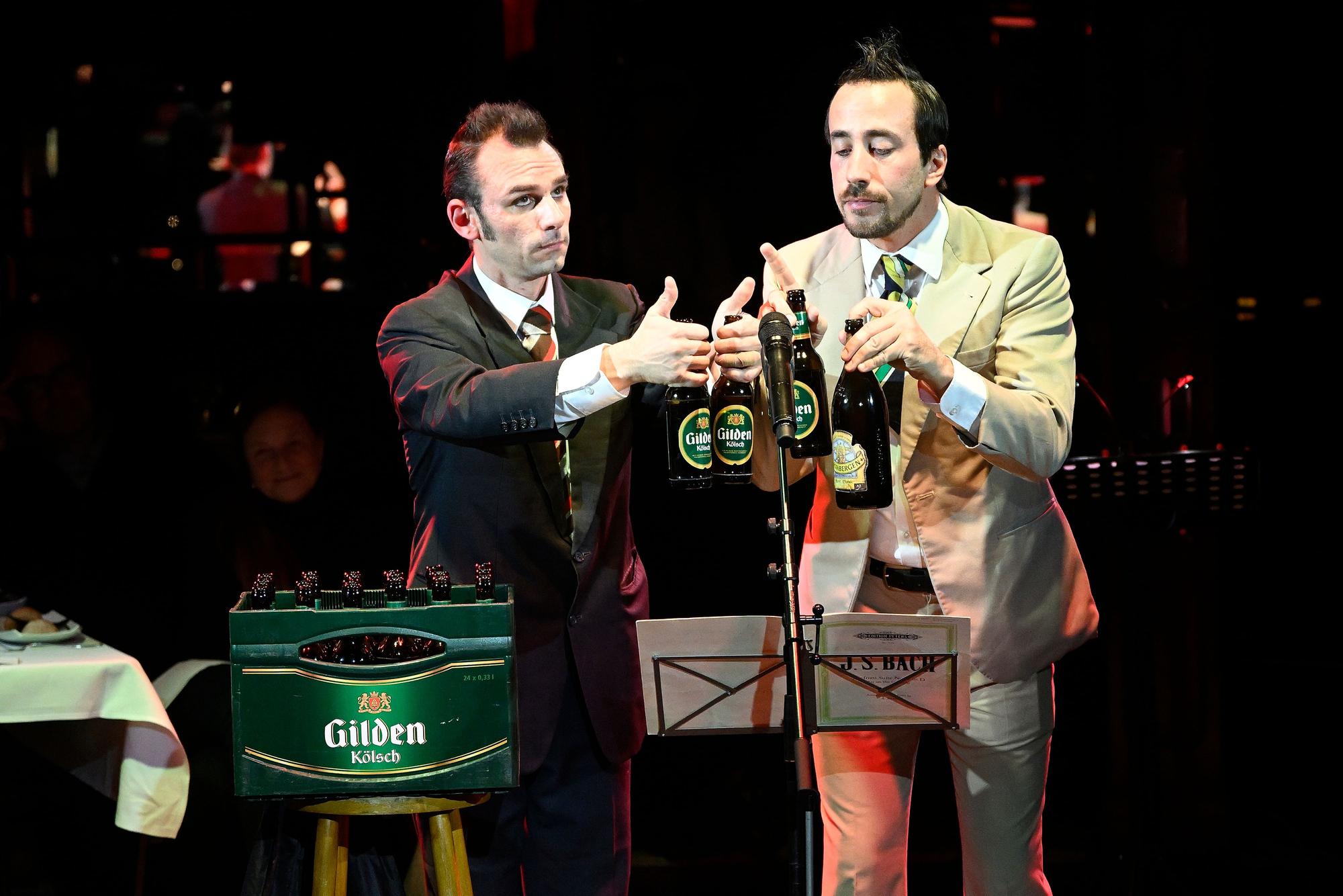 Zwei Clowns musizieren mit Bierflaschen.