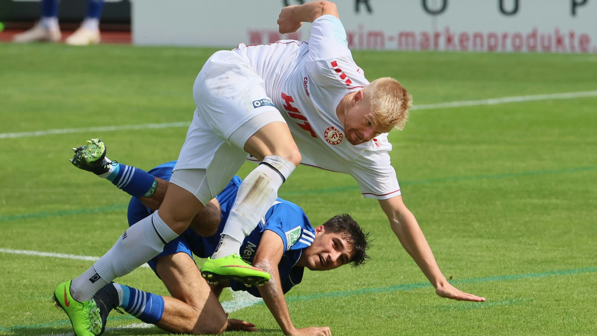 Ein Fußballspieler gerät bei einem Zweikampf ins Stolpern.