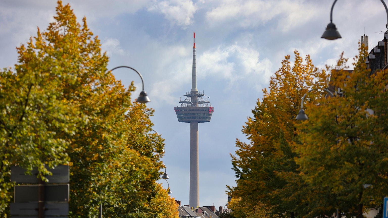 Das Bild zeigt den Blick auf den Fernsehturm "Colonius", im Vordergrund sind links und rechts Bäume zu sehen.