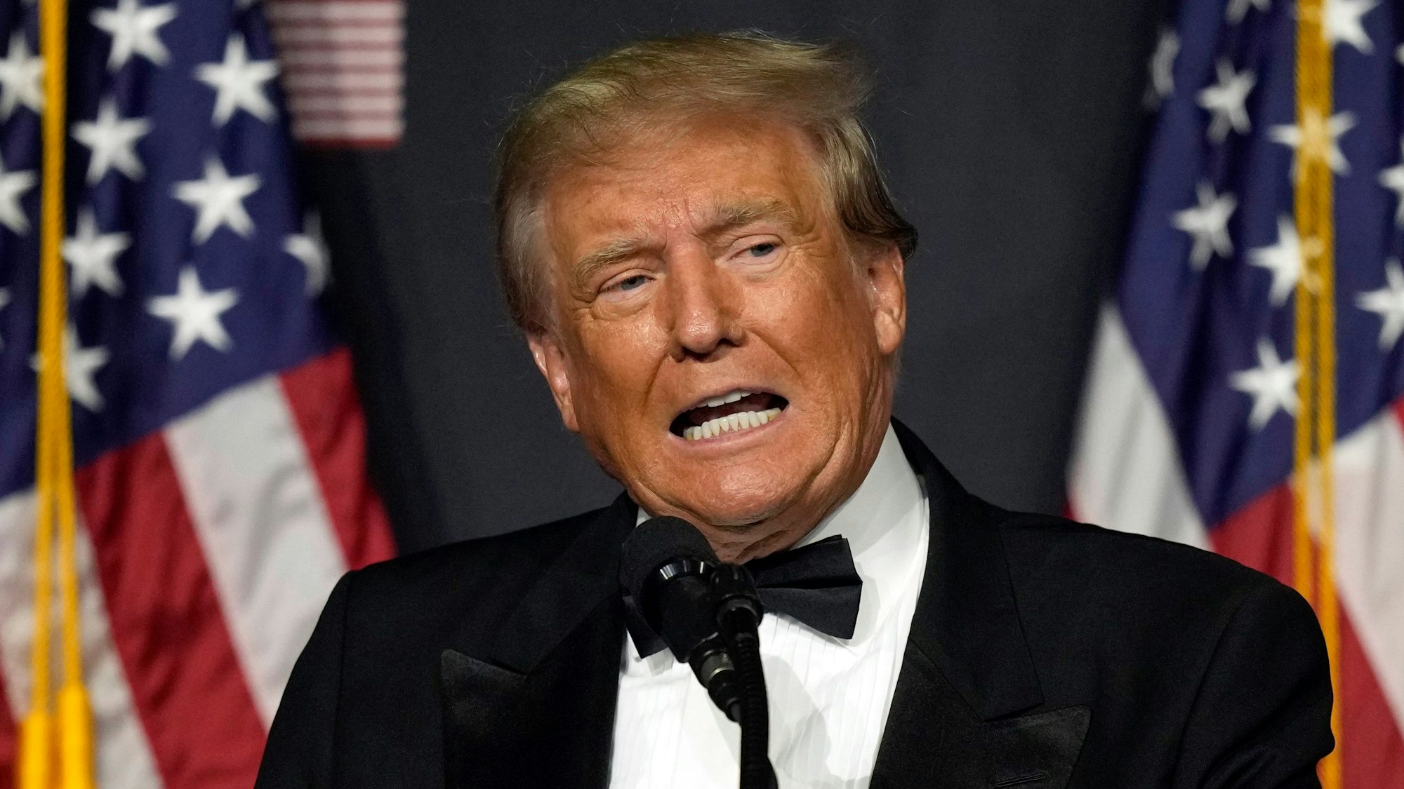 Donald Trump, ehemaliger Präsident der USA, spricht in Mar-a-Lago in Palm Beach, Florida auf einem Podest vor zwei US-amerikanischen Flaggen.