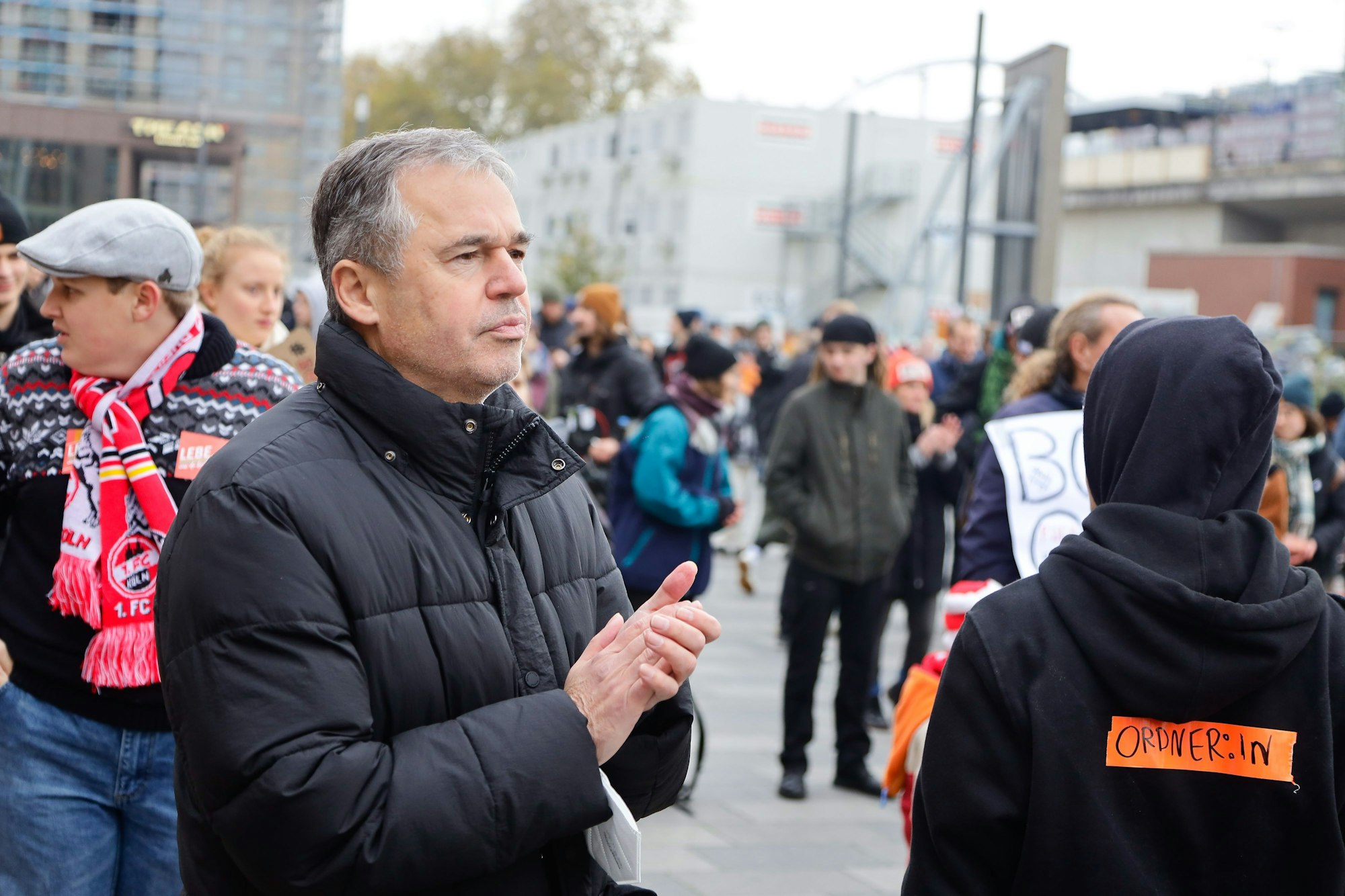 Fußballfunktionär Andreas Rettig steht während einer Demonstration gegen die Fußball-WM in Katar auf dem Barmer Platz in Deutz und applaudiert.