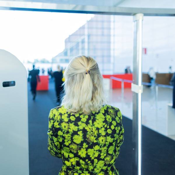 Eine Besucherin der Art Cologne geht im grünen Blumenkleid durch eine Sicherheitskontrolle mit Körperscannern.