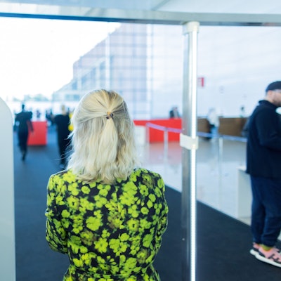 Eine Besucherin der Art Cologne geht im grünen Blumenkleid durch eine Sicherheitskontrolle mit Körperscannern.