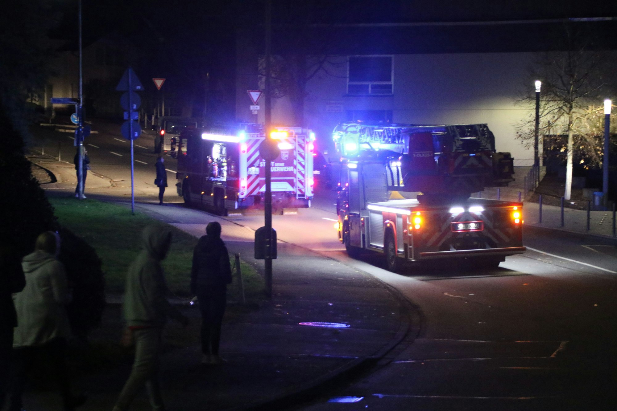 Zwei Feuerwehrautos, deren Blaulicht im Dunkeln gut zu sehen, stehen vor der Eugen-Haas-Halle in Gummersbach.