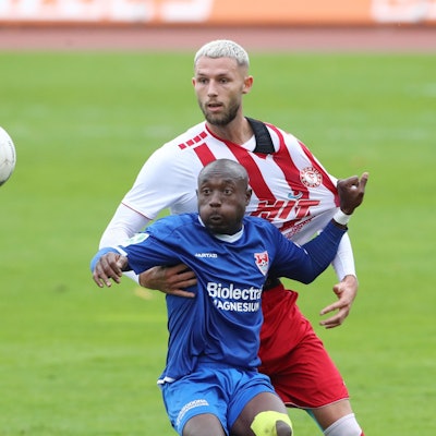 Ein Fußballspieler blickt im Zweikampf auf den Ball und zieht seinem Gegenspieler am Trikot.