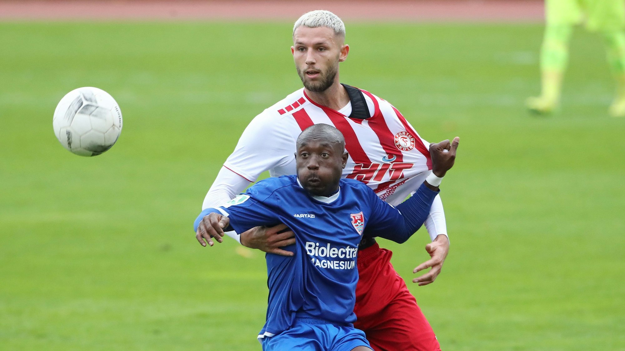 Ein Fußballspieler blickt im Zweikampf auf den Ball und zieht seinem Gegenspieler am Trikot.