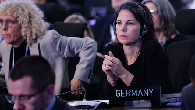 Bundesaußenministerin Annalena Baerbock (Grüne) schaut skeptisch und hat in einem Konferenzsaal Kopfhörer auf. Vor ihr steht ein Schild, auf dem „Germany“ steht.