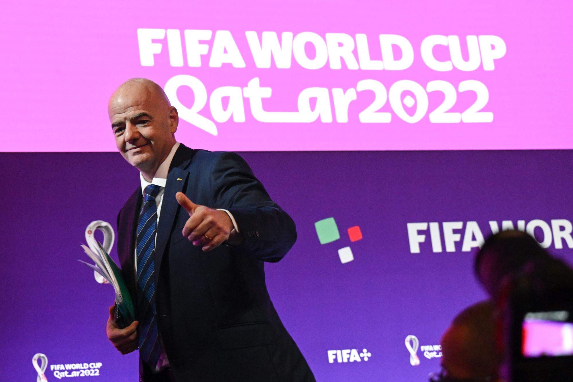 FIFA-Präsident Gianni Infantino steht vor einer Pressewand mit dem Logo der WM 2022 in Katar und hebt den Daumen nach oben.