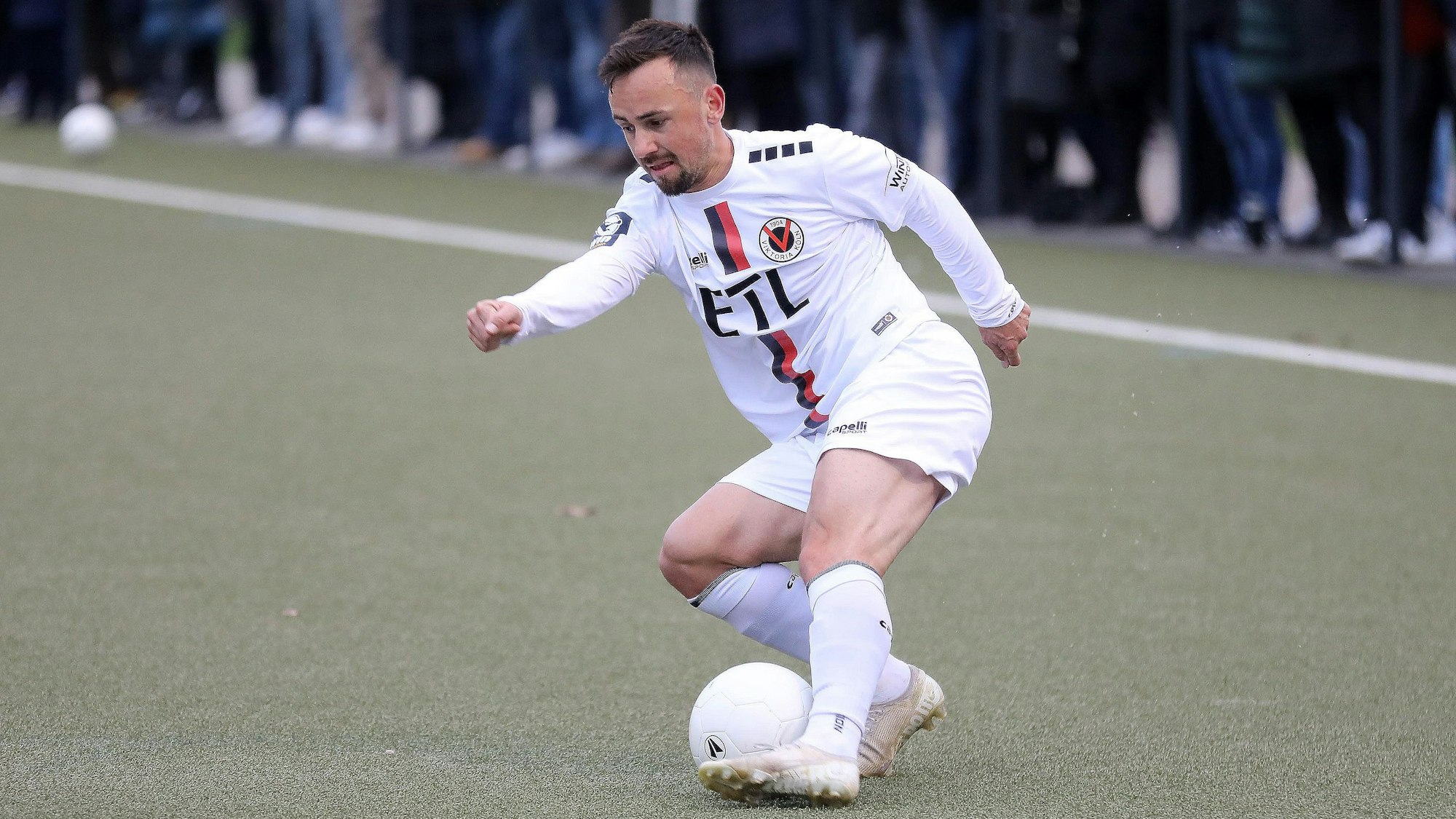 Ein Fußballspieler führt den Ball mit dem linken Fuß.