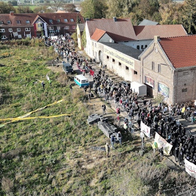 Lützerath von oben gesehen: Bei einer Demonstration in Lützerath ziehen mehrere Hundert Teilnehmer mit Banner durch das Dorf.