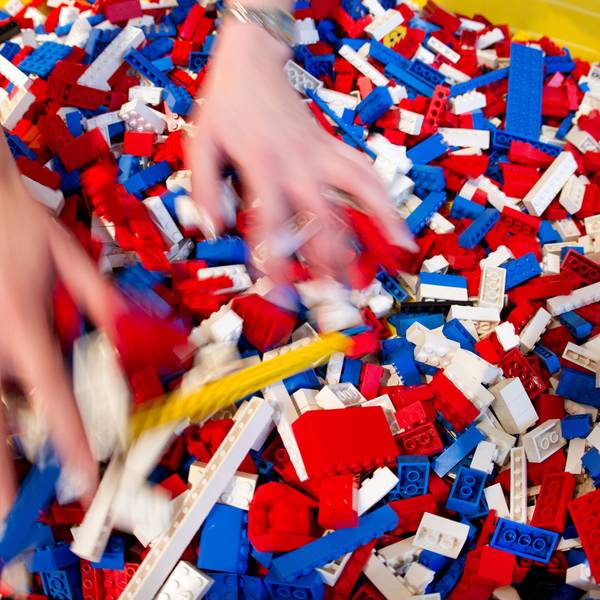 Zwei Hände wühlen in einem bunten Haufen aus Legosteinen.
