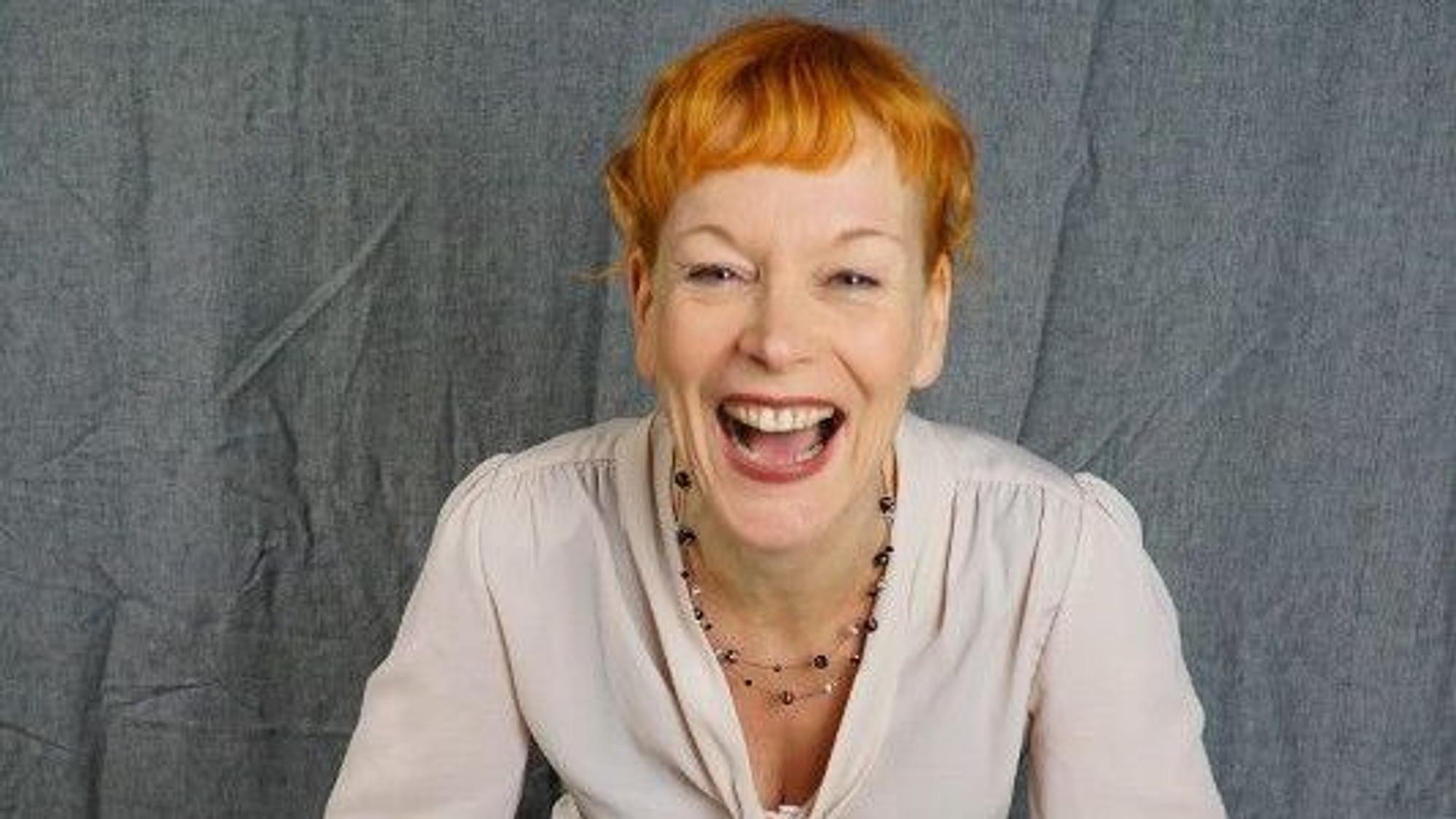 Schauspielerin Britta Weyers sitzt auf einem bunt bemalten Holzhocker.