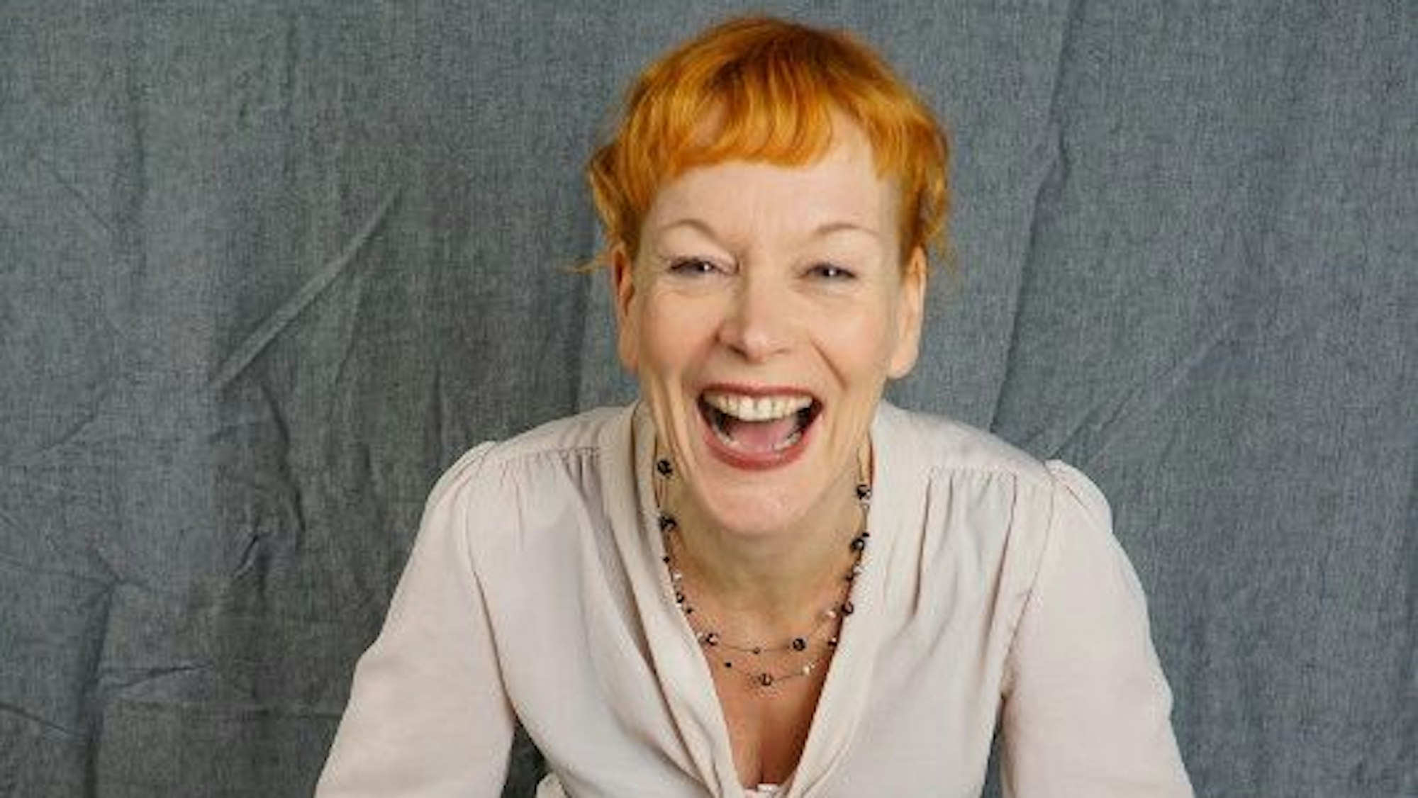 Schauspielerin Britta Weyers sitzt auf einem bunt bemalten Holzhocker.