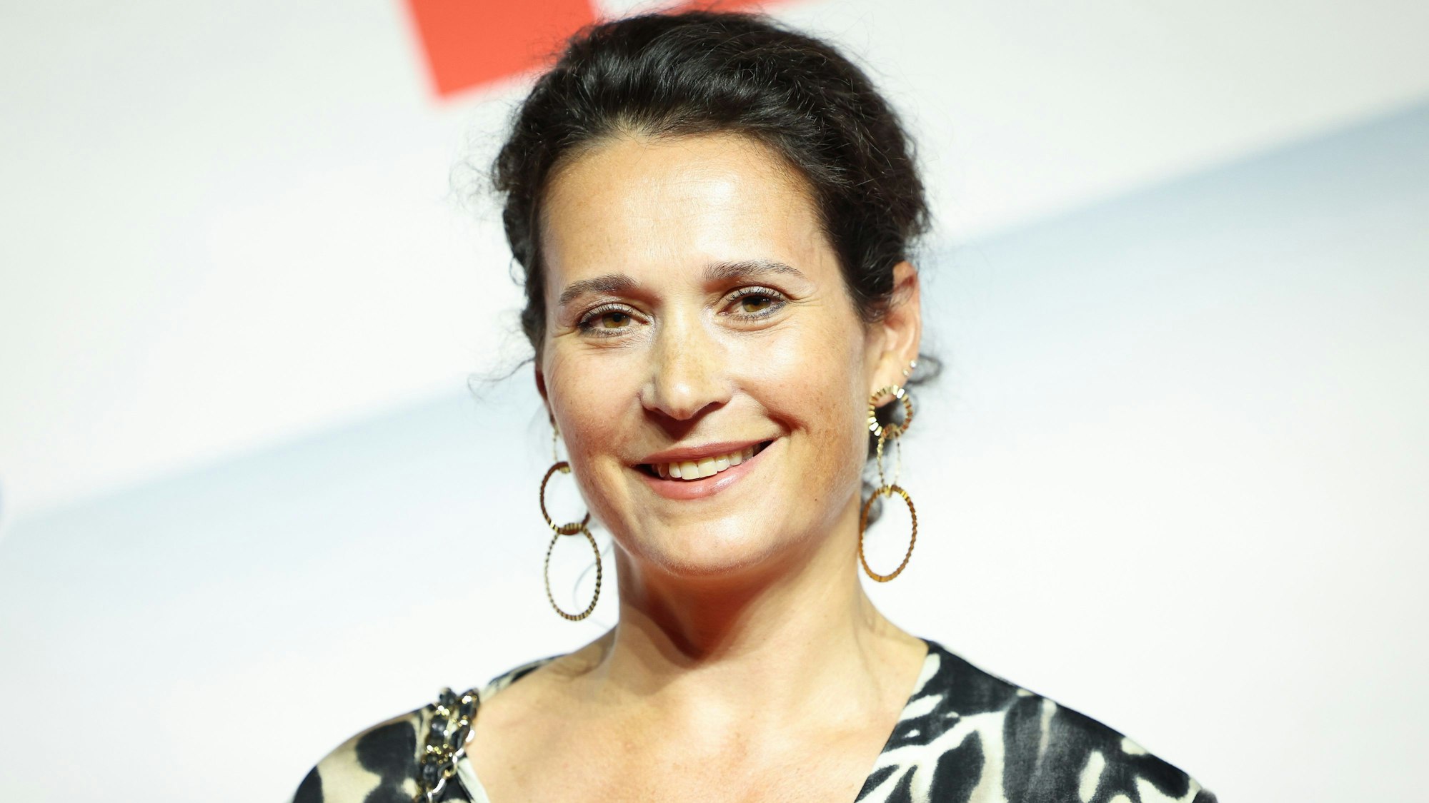 Ulrike Handel, Vorständin bei Axel Springer SE, steht vor einem weißen Hintergrund mit rotem Aufdruck.