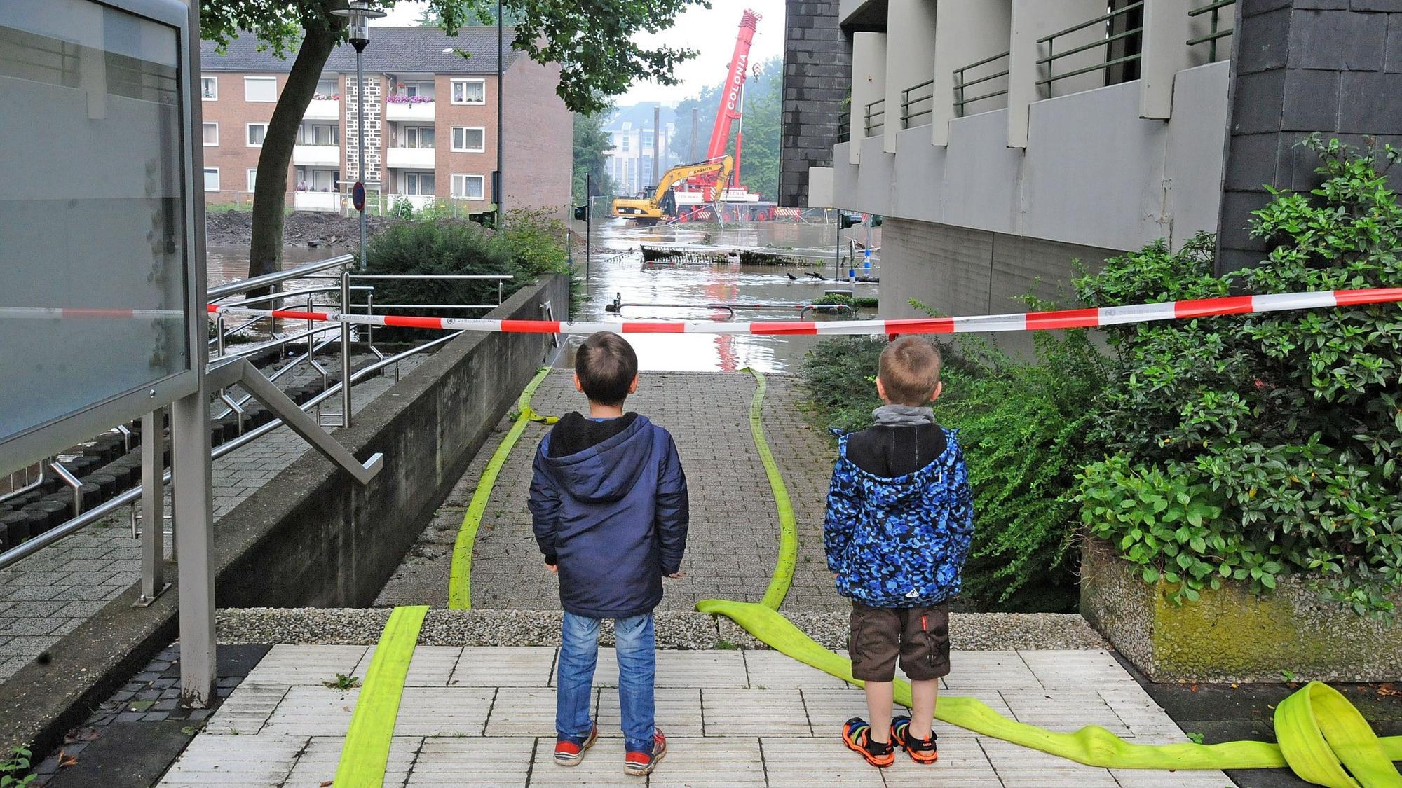 Zwei Kinder stehen auf der Leichlinger Rathaus-Treppe und blicken auf das Wupper-Hochwasser