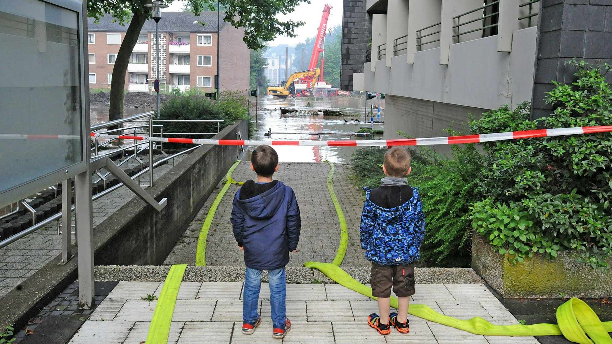 Zwei Kinder stehen auf der Leichlinger Rathaus-Treppe und blicken auf das Wupper-Hochwasser