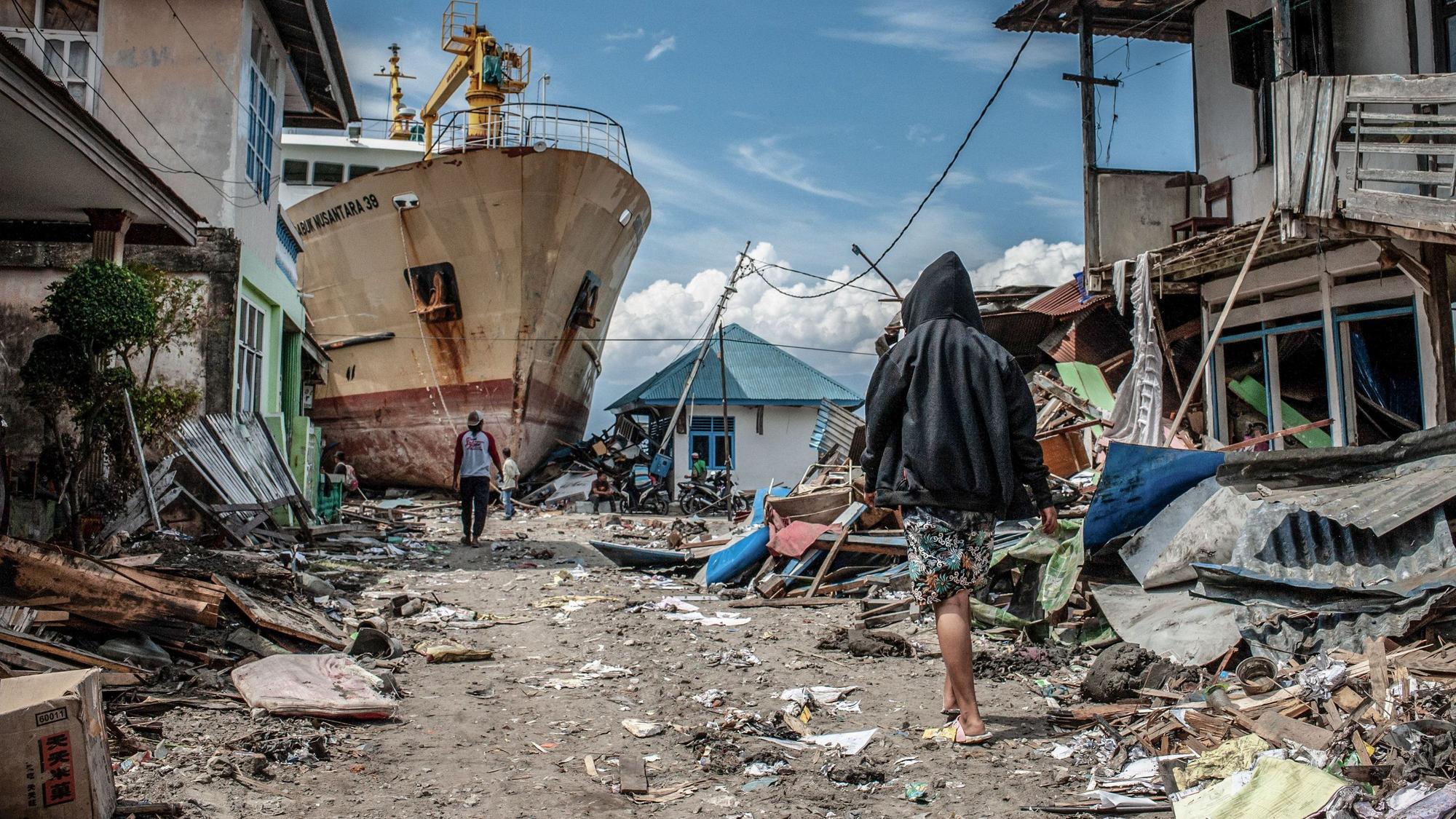 Auf dem Archivbild vom 06.10.2018, gehen Menschen in Palu (Indonesien) eine Straße entlang.Rund 5000 Menschen wurden damals nach einem Erdbeben und einem Tsunami in Indonesien vermisst.