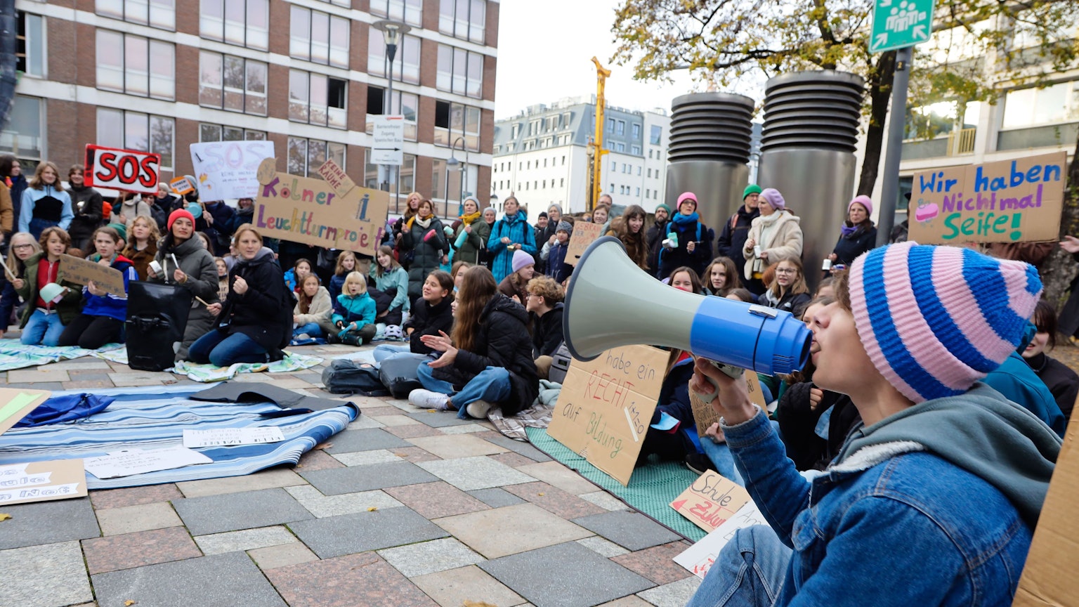 Auf Picknickdecken und mit ohrenbetäubendem Lärm weisen die Schüler darauf hin, dass sie weder Mensa noch Fachräume haben.
