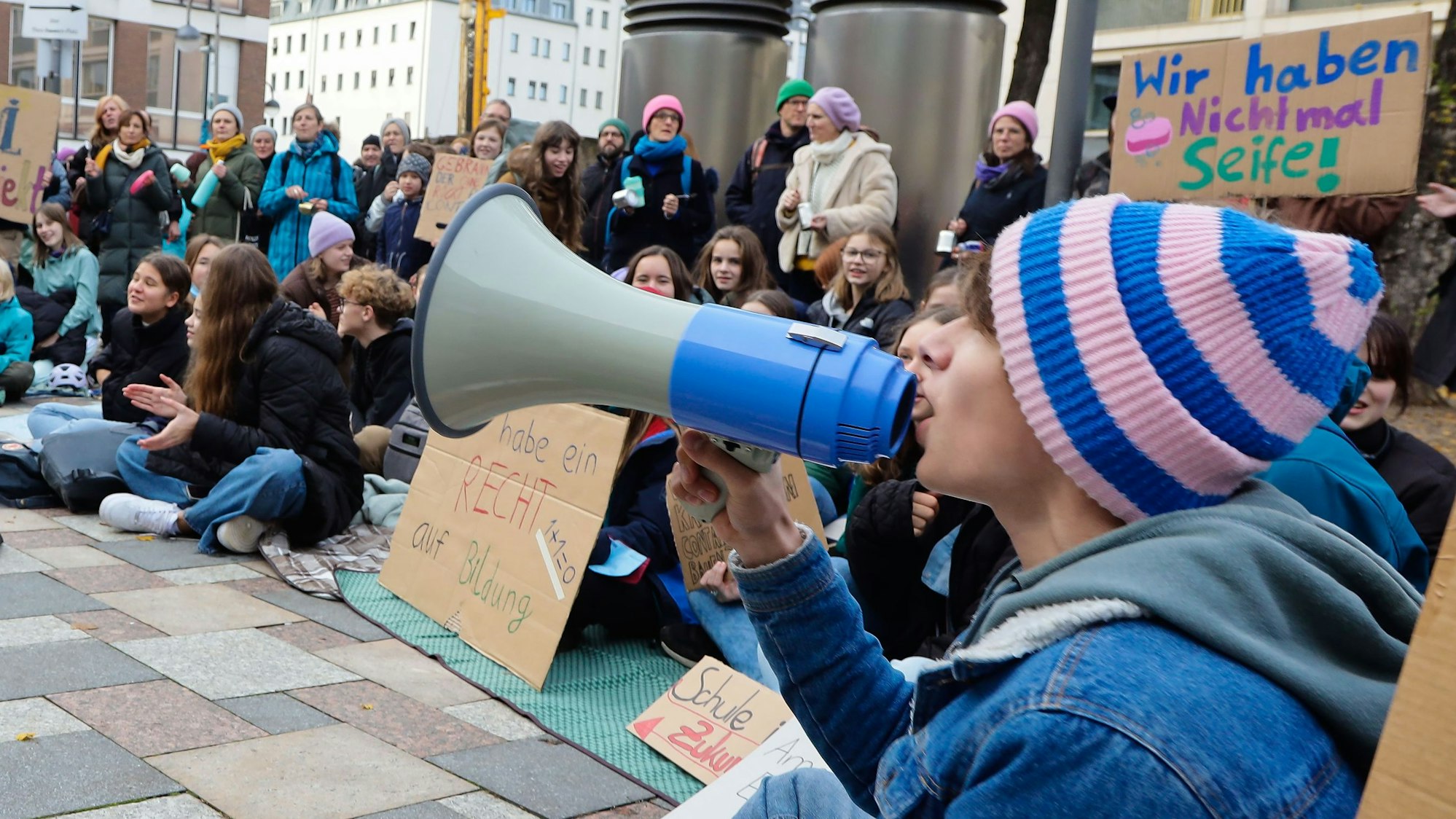 Auf Picknickdecken und mit ohrenbetäubendem Lärm weisen die Schüler darauf hin, dass sie weder Mensa noch Fachräume haben.