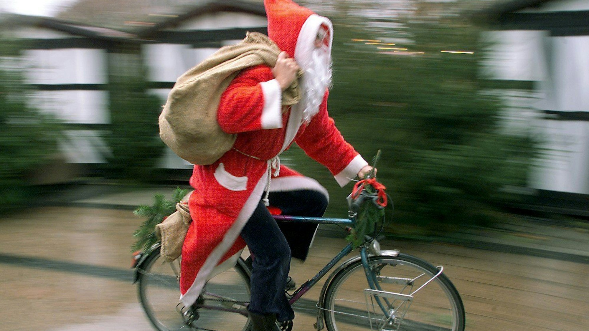 Mit rasantem Tempo fährt ein als Nikolaus verkleideter Mann auf seinem Fahrrad durch eine Fußgängerzone.