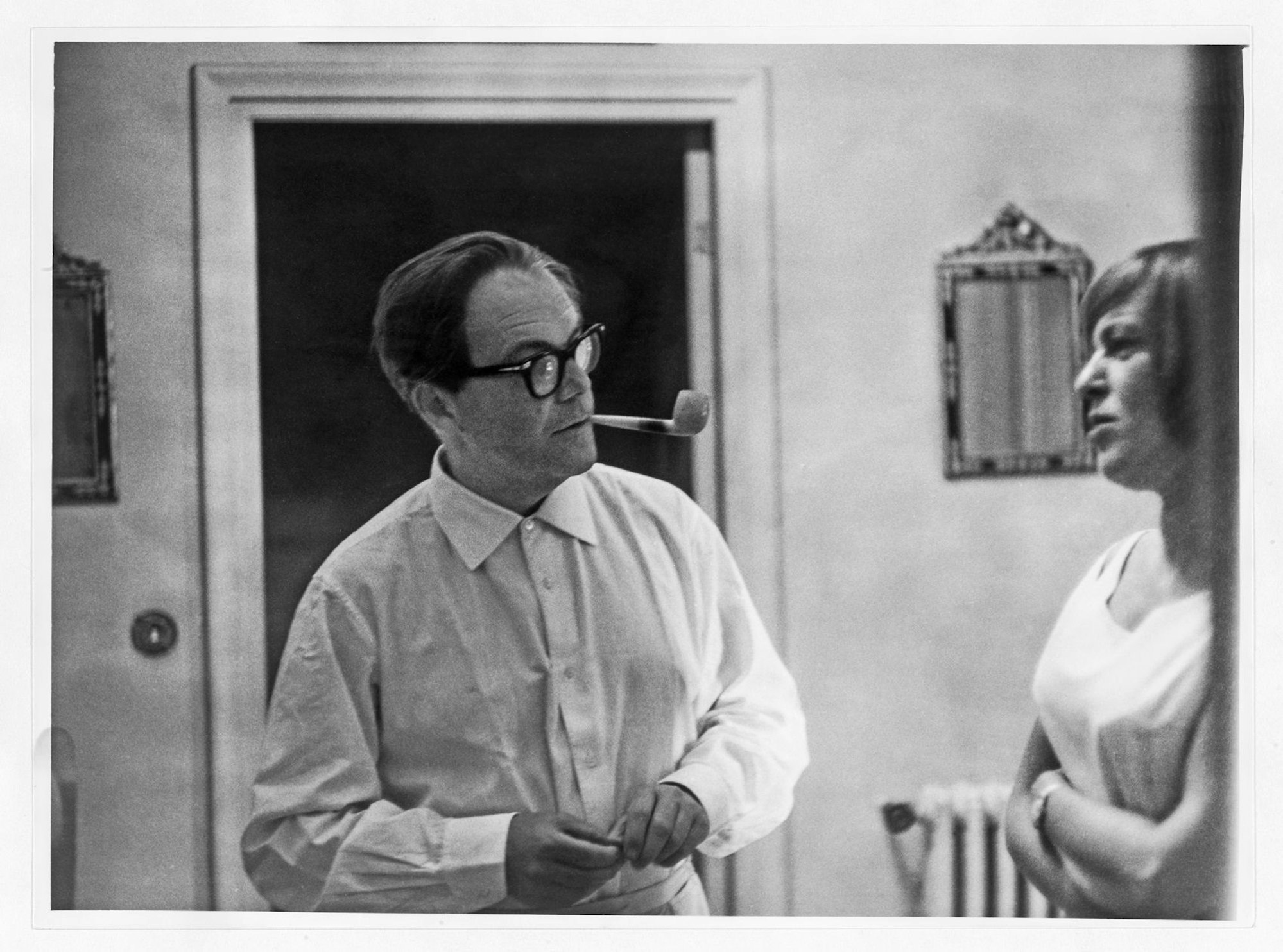 Max Frisch schaut zu Ingeborg Bachmann, er hat eine Pfeife im Mund. Bachmann hält die Arme überkreuzt.