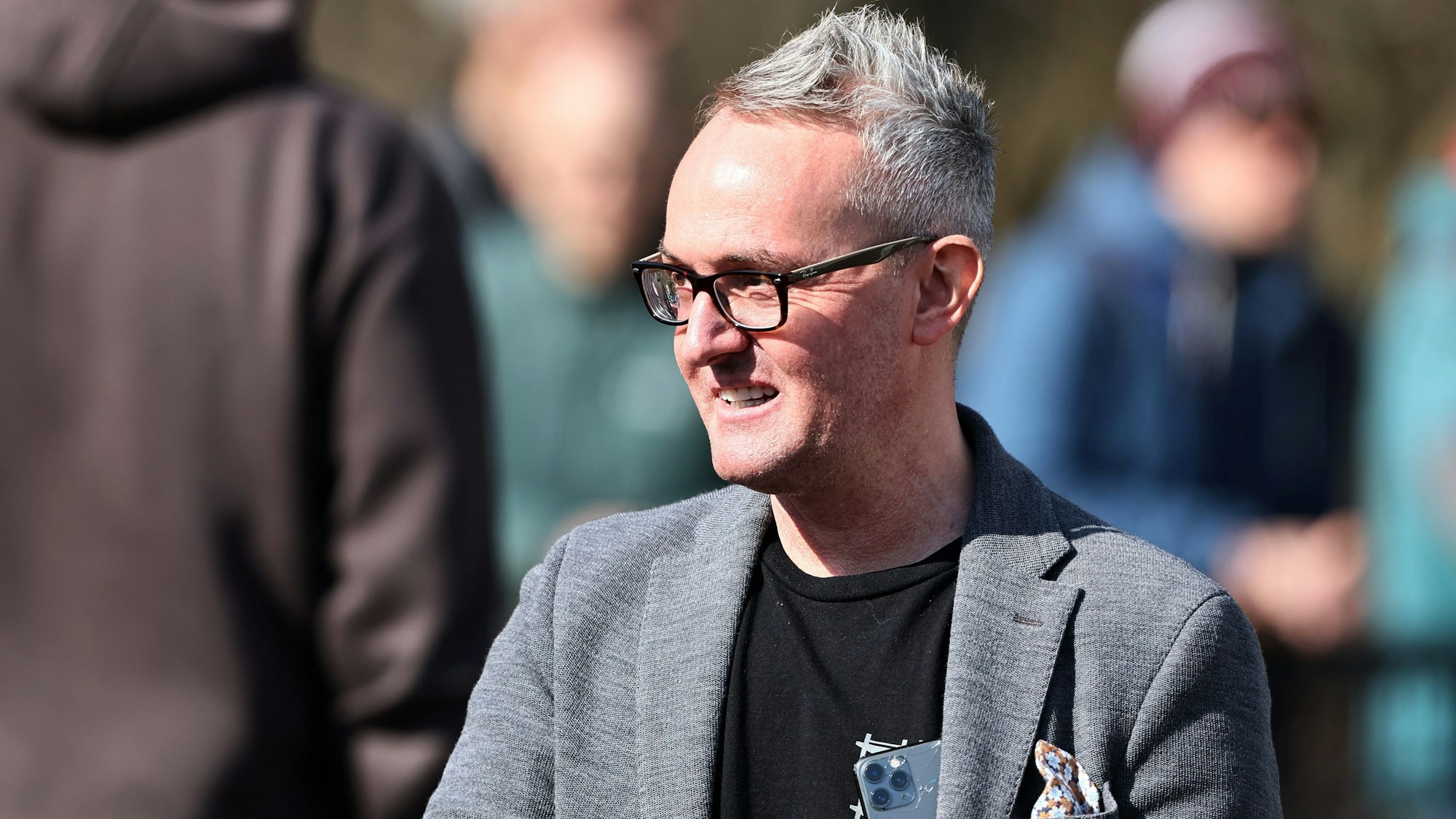 Alexander Wehrle steht in einem Sakko auf einem Fußballfeld. Er wurde im März beim 1. FC Köln verabschiedet