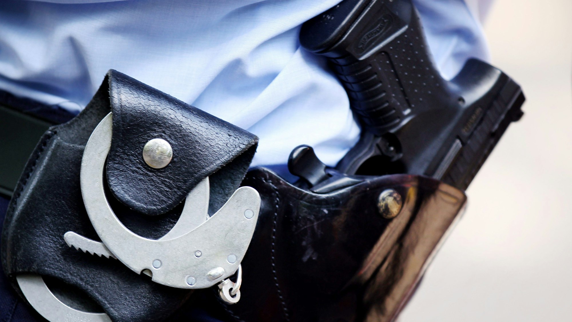 Ein Polizist mit Handschellen und Pistole am Gürtel steht in Köln.