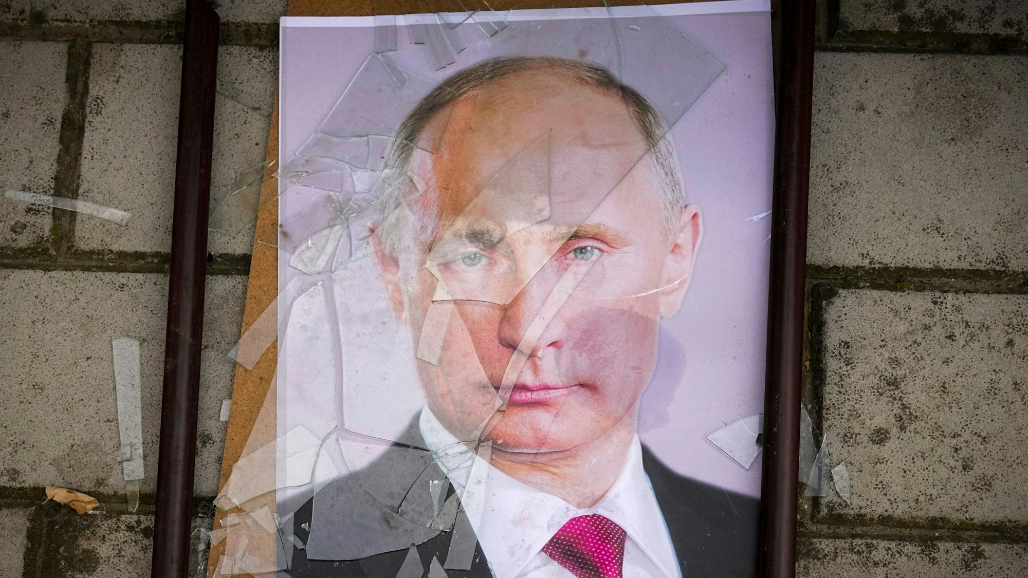 Ein zersprungenes Bild des russischen Präsidenten Wladimir Putin liegt auf dem Boden.