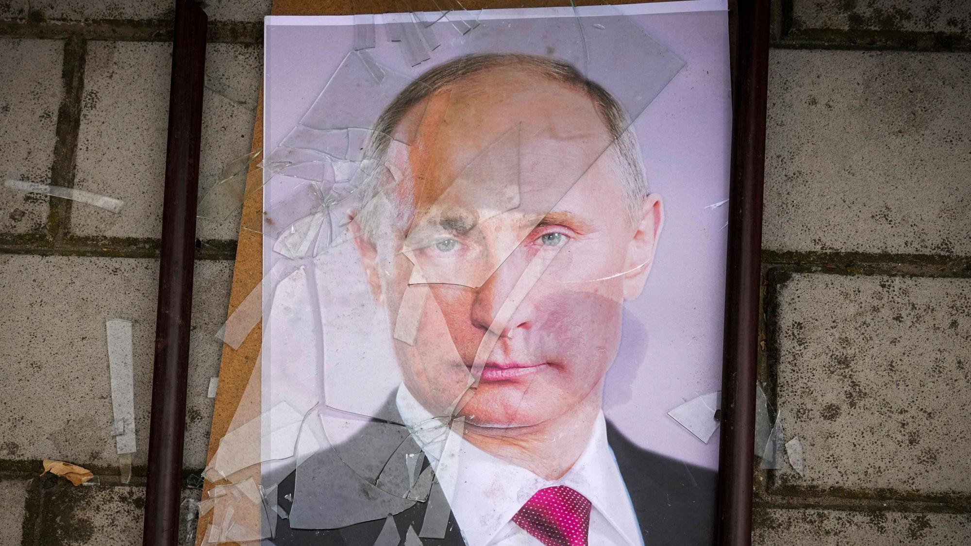 Ein zersprungenes Bild des russischen Präsidenten Wladimir Putin liegt auf dem Boden.